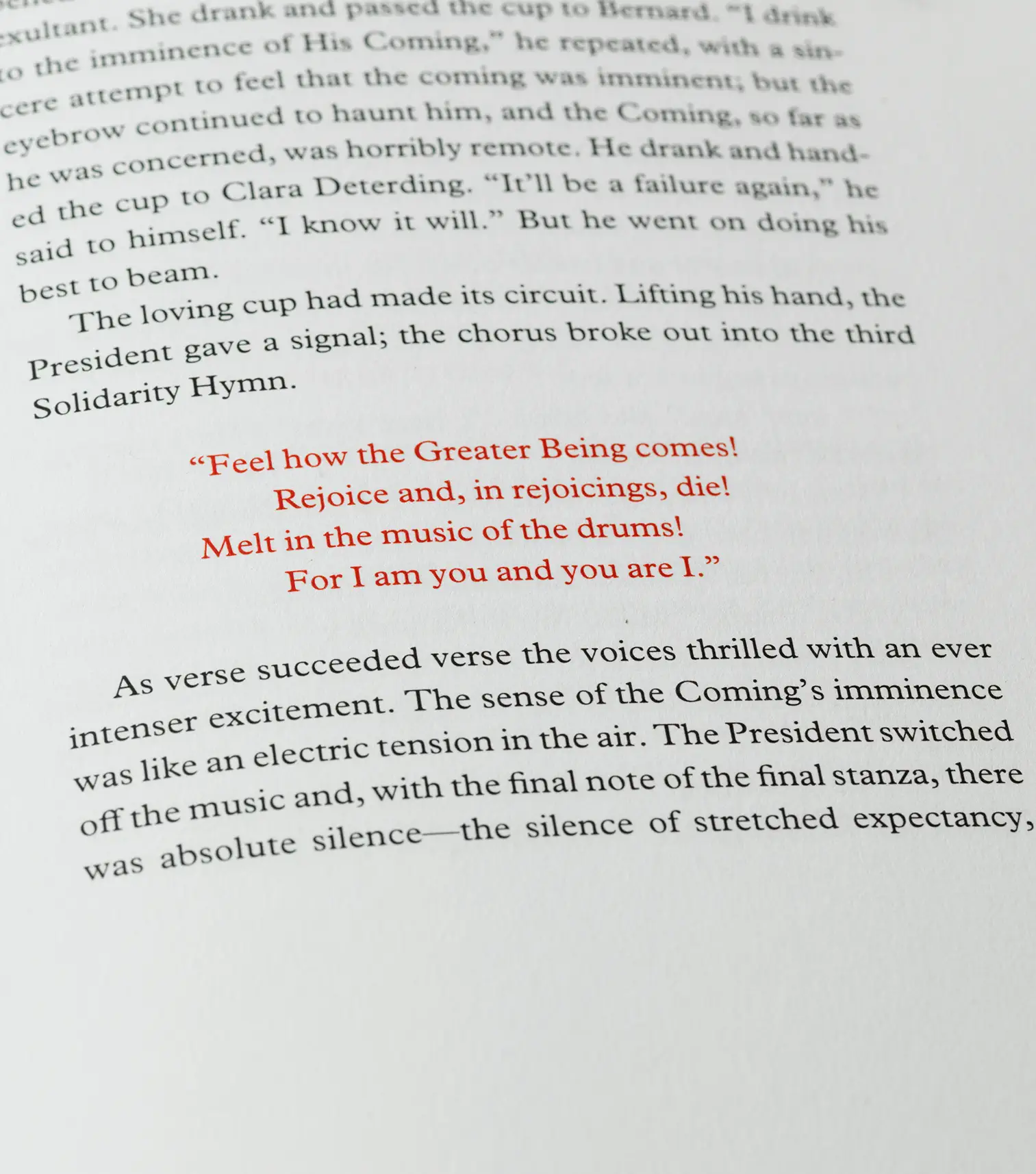 A letterpress page from the Areté Editions Brave New World. Two blocks of black text describing a Solidarity Service surround the third Solidarity Hymn, which is printed in red and centred on the page.