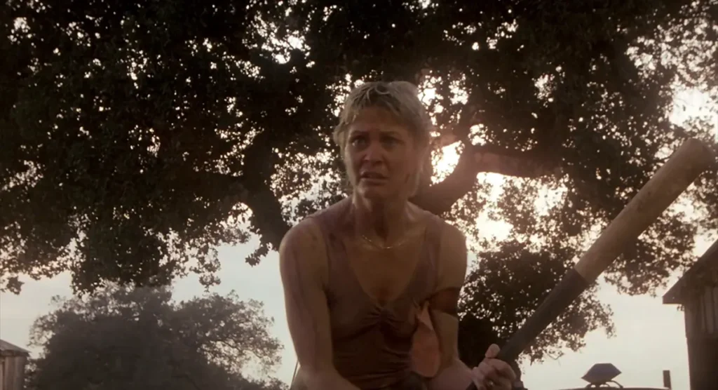 Dee Wallace as Donna Trenton standing in the Camber dooryard gripping a baseball bat in the 1983 film Cujo.