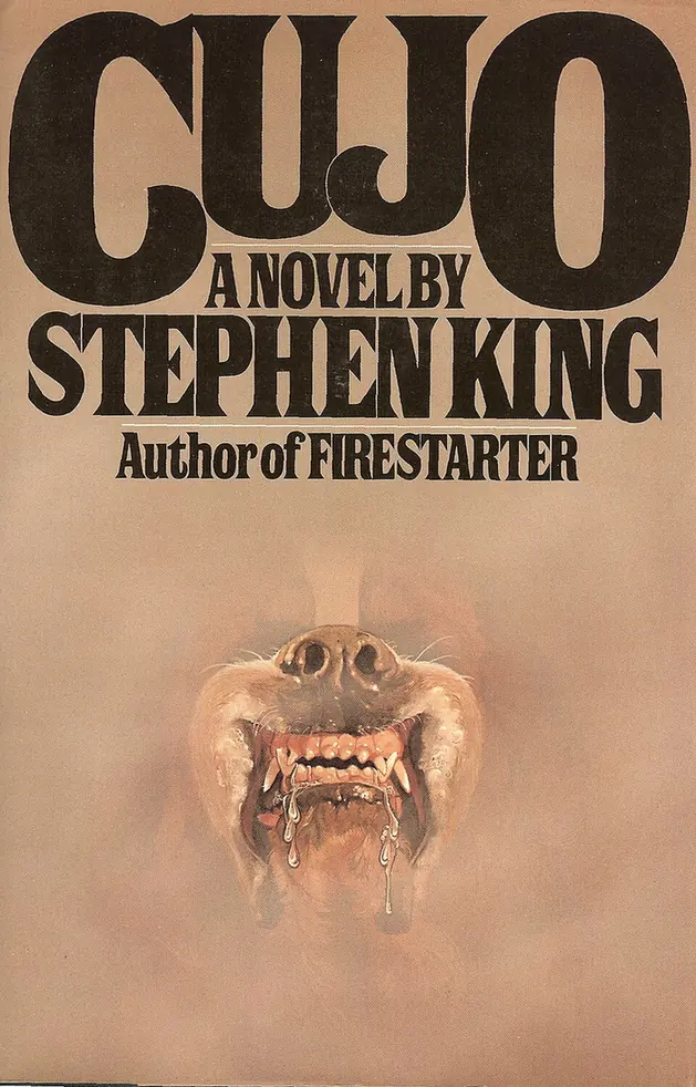 First edition cover of Cujo by Stephen King, a snarling Saint Bernard's muzzle dripping foam, emerging from a pale haze below the title.