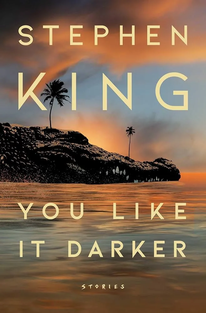 First edition cover of You Like It Darker by Stephen King, a small palm-covered island under an orange sunset sky.